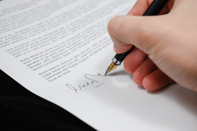 Person signing a written document with a pen.