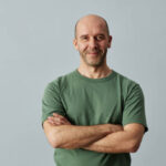 Smiling man in green t-shirt arms crossed.