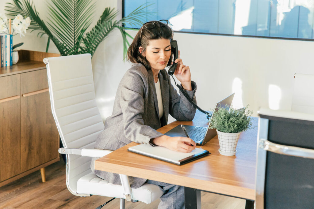 Businesswoman on phone writing notes at desk
