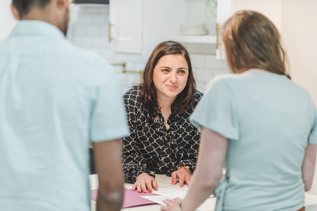 Woman meeting with two people in kitchen.