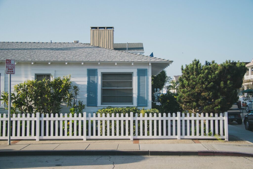 Cozy house with white picket fence and trees.